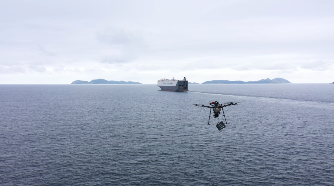 dron con carga volando en el agua hacia un barco